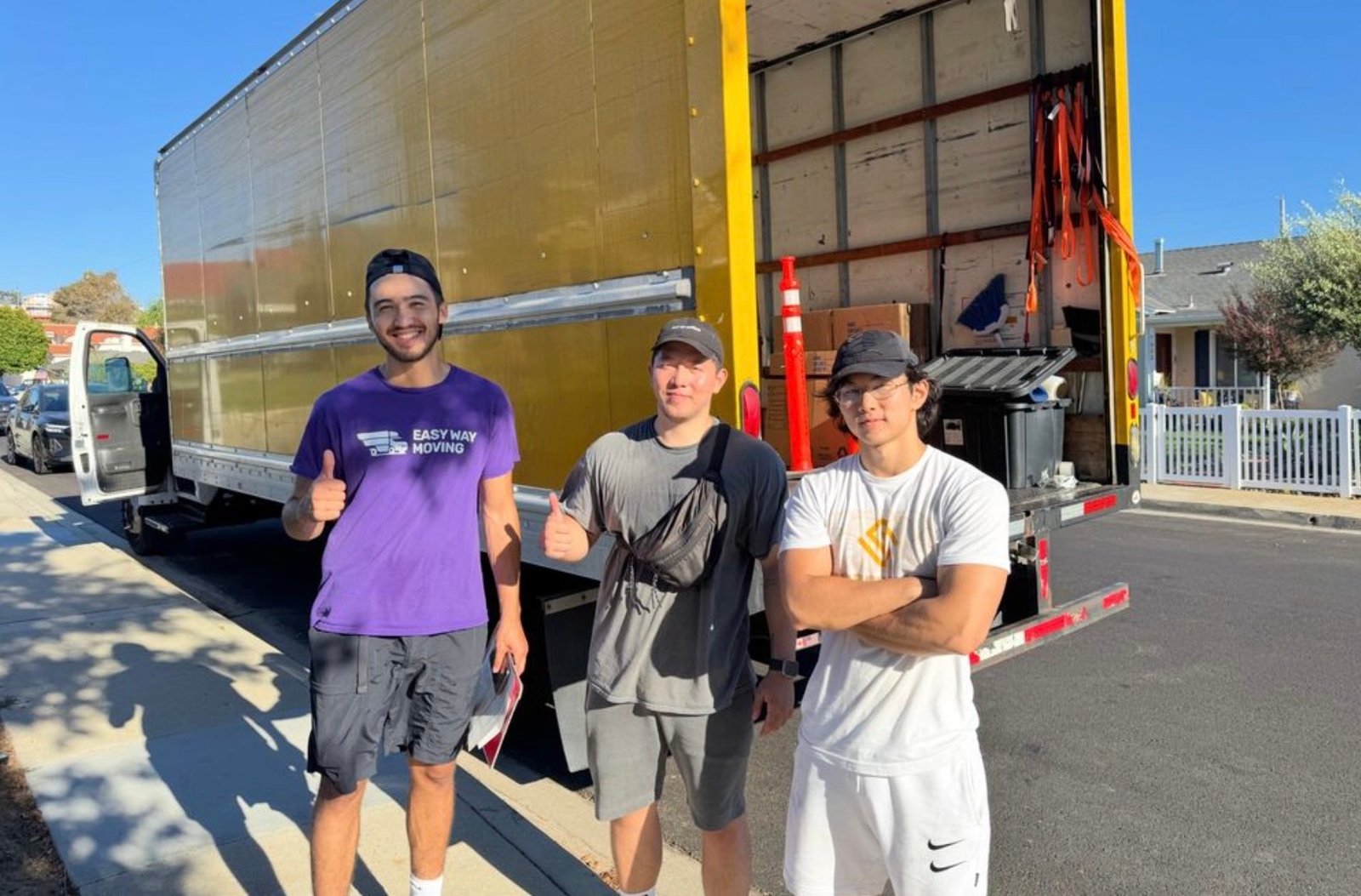 Easy Way Moving crew standing in front of their open moving truck on a residential street